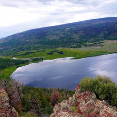 A panoramic view of a serene lake nestled atop a mountain, offering mental health solace and therapy amidst an alcohol rehab center.