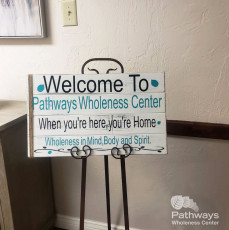 A wooden sign that welcomes individuals to a holistic mental health care center.