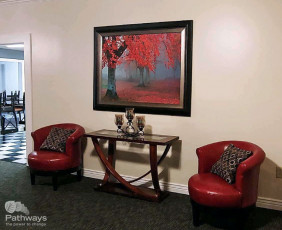 A living room with red chairs and a painting on the wall in a drug addiction treatment center.