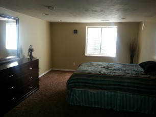 A mental health care facility with a bedroom furnished with a dresser and mirror.