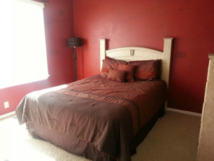A drug rehab in Utah providing mental health care within a bedroom featuring red walls and a brown bed.