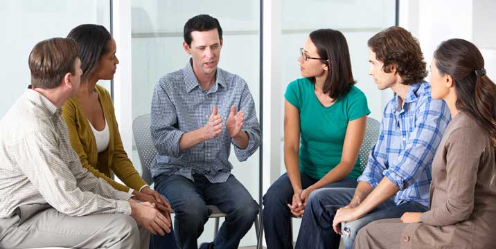 A group of people sitting in a circle talking during a drug addiction treatment.