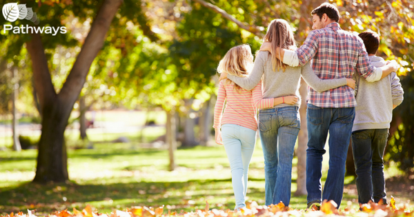 A group of people receiving mental health care walking through a park.